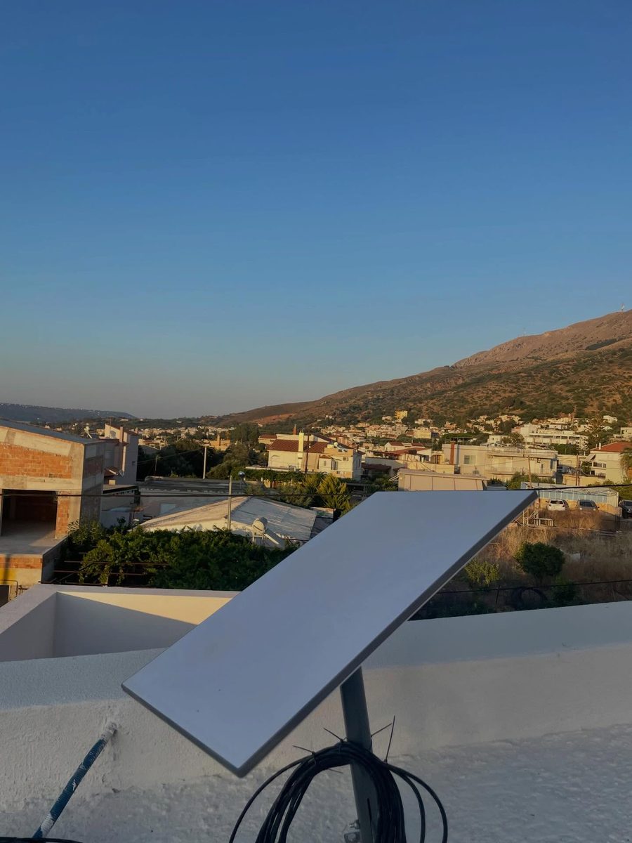 Κεραία Starlink σε επίτοιχη βάση με τακτοποιημένη καλωδίωση, με φόντο χωριό και βουνό στην Κρήτη